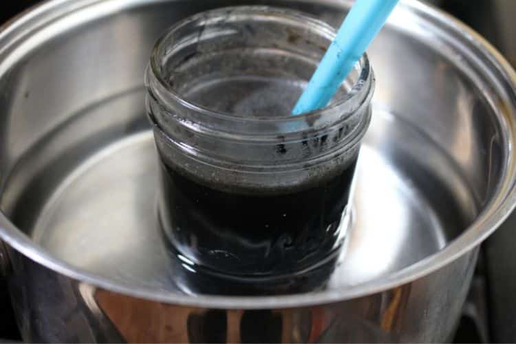 image of making black drawing salve in mason jar in pot of water