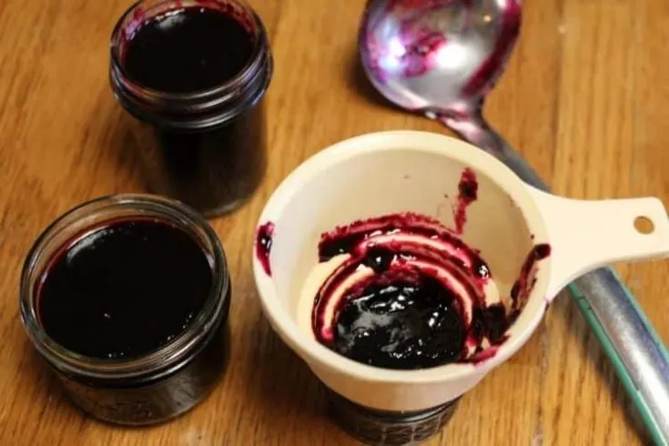 jars with grape jam being ladeled into them