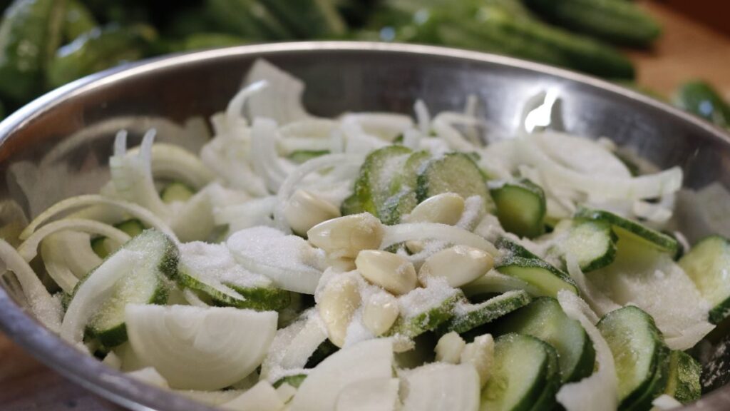 bowl of cucumbers, onions and garlic with salt on them